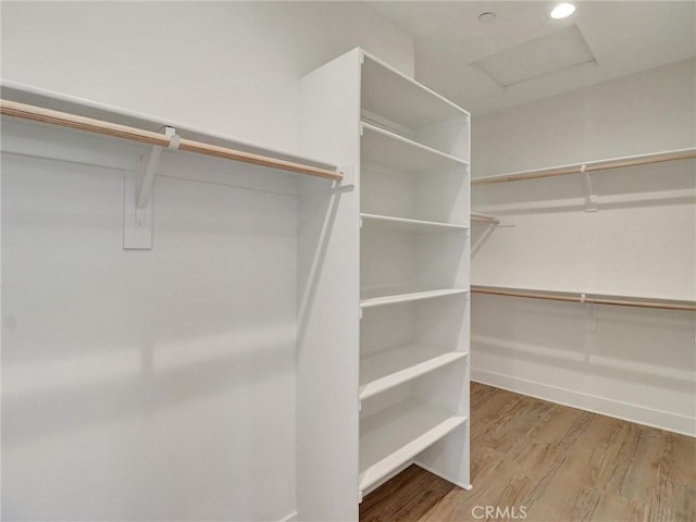 walk in closet featuring attic access and wood finished floors