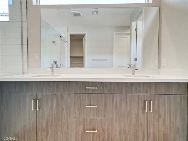 full bath with a sink, visible vents, and double vanity