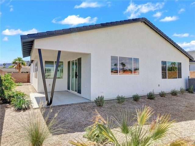 rear view of house featuring stucco siding, a patio, and fence