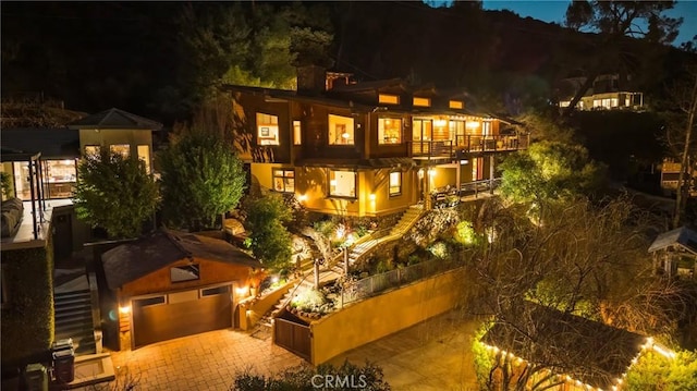 back of house at night featuring a garage