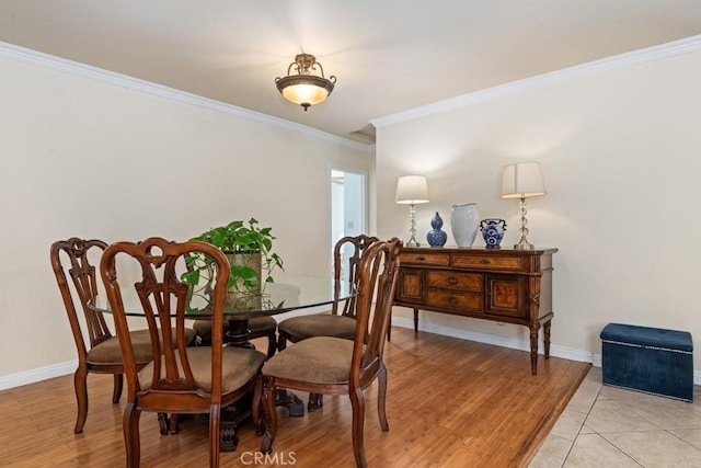 dining room featuring light wood-style floors, baseboards, and ornamental molding