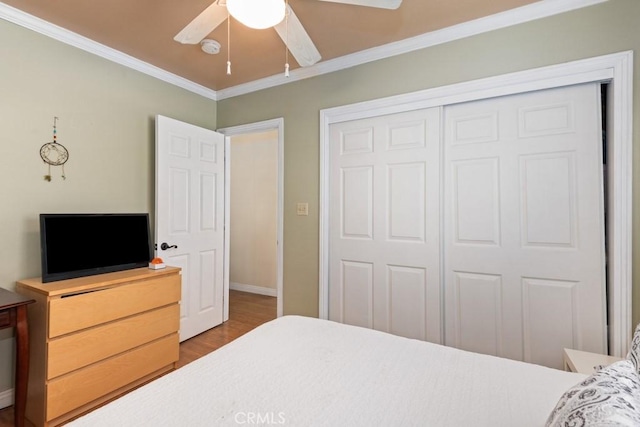 bedroom featuring wood finished floors, baseboards, ceiling fan, ornamental molding, and a closet