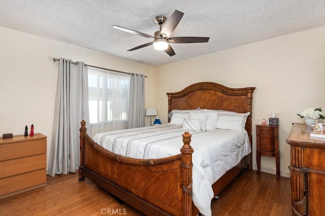 bedroom with a textured ceiling, a ceiling fan, and wood finished floors