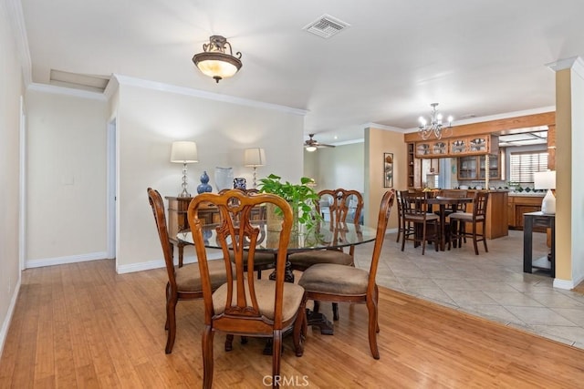 dining room featuring light tile patterned floors, baseboards, visible vents, ornamental molding, and ceiling fan with notable chandelier