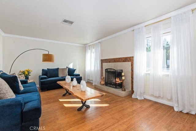 living room with visible vents, light wood-style flooring, and a tile fireplace