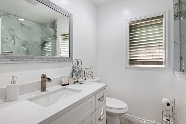 bathroom featuring a marble finish shower, toilet, and vanity