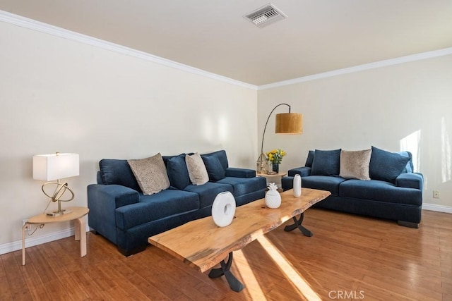 living room with visible vents, baseboards, light wood-style floors, and crown molding