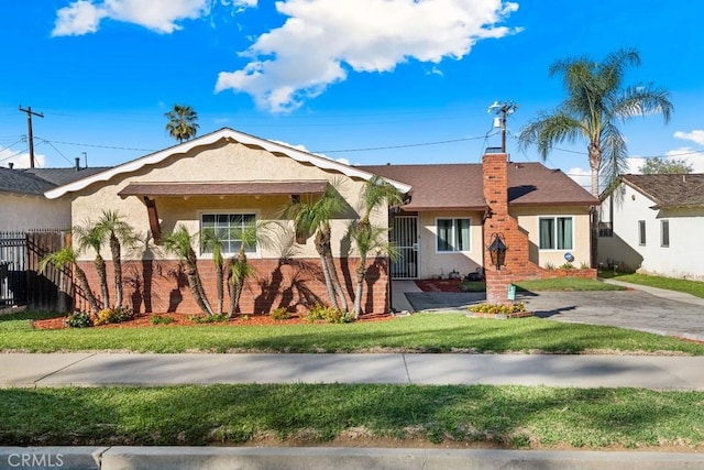 ranch-style house with brick siding, a front lawn, fence, stucco siding, and a chimney