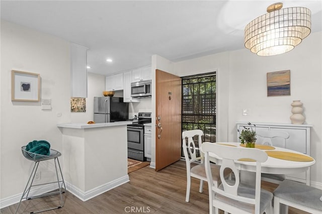 kitchen featuring dark wood finished floors, white cabinetry, a peninsula, appliances with stainless steel finishes, and light countertops