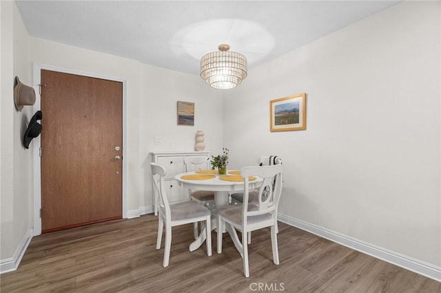 dining area with baseboards, a notable chandelier, and wood finished floors