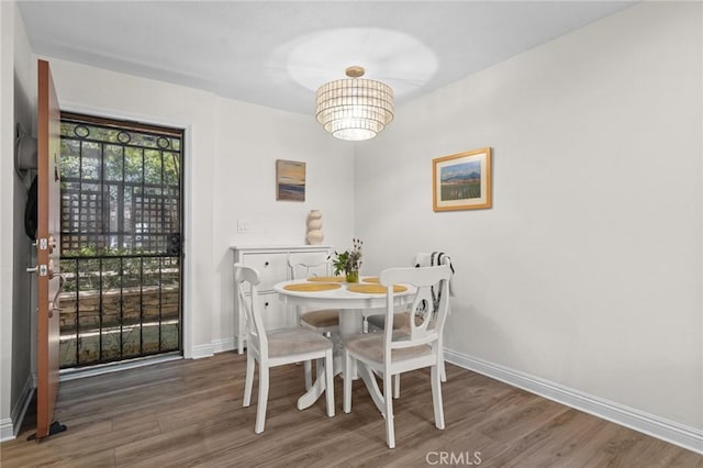 dining space with wood finished floors, baseboards, and a chandelier