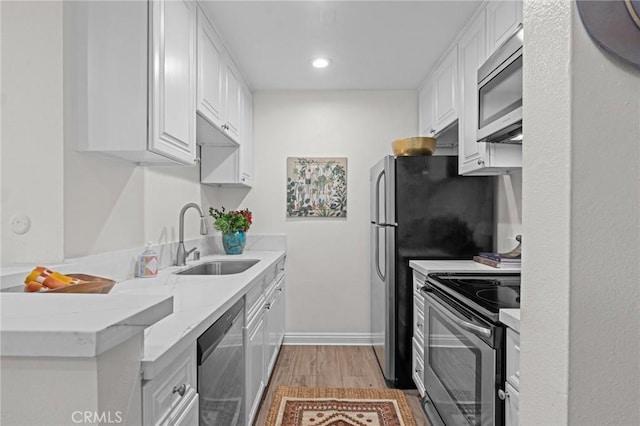 kitchen featuring white cabinets, recessed lighting, stainless steel appliances, a sink, and light wood-style floors