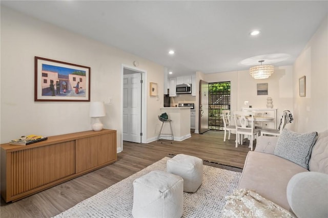 living area featuring baseboards, wood finished floors, and recessed lighting