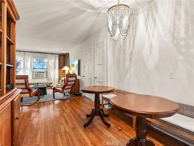 dining room with light wood-type flooring, a notable chandelier, and cooling unit