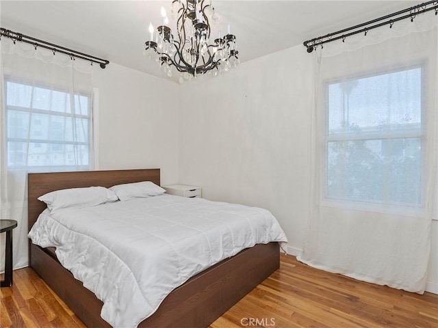 bedroom featuring a chandelier and wood finished floors