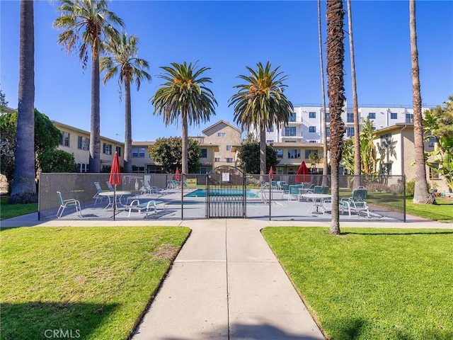 view of home's community featuring a yard, a residential view, a swimming pool, and fence