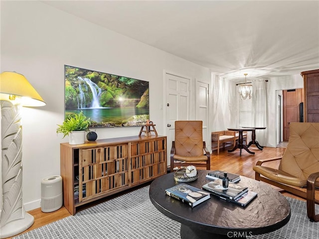 living room featuring a notable chandelier, wood finished floors, and baseboards