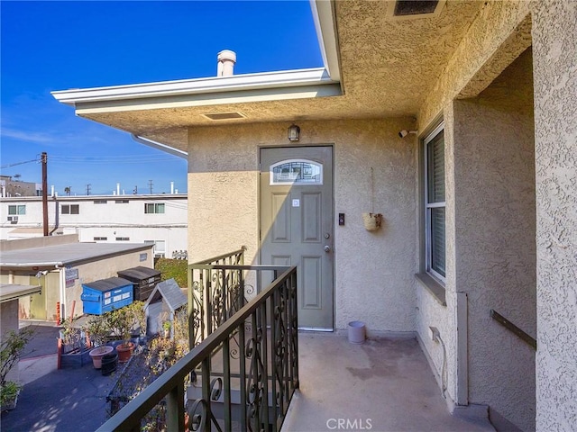 entrance to property with stucco siding and a balcony