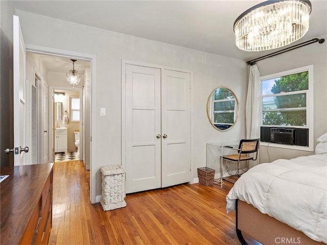 bedroom featuring a closet, a notable chandelier, cooling unit, and hardwood / wood-style floors