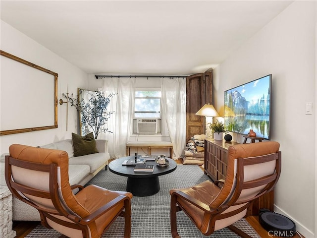 living area featuring cooling unit, baseboards, and wood finished floors