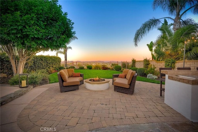 patio terrace at dusk featuring fence private yard and an outdoor living space with a fire pit