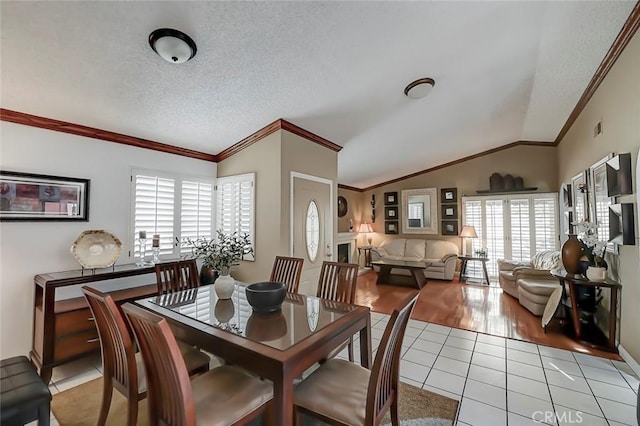 dining room with light tile patterned floors, a textured ceiling, lofted ceiling, and ornamental molding