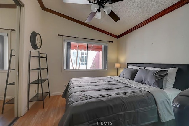 bedroom with lofted ceiling, crown molding, light wood finished floors, baseboards, and ceiling fan