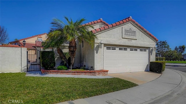 mediterranean / spanish home with a tiled roof, a front yard, stucco siding, driveway, and a gate