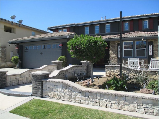 view of front of property with a tiled roof, an attached garage, stone siding, and driveway