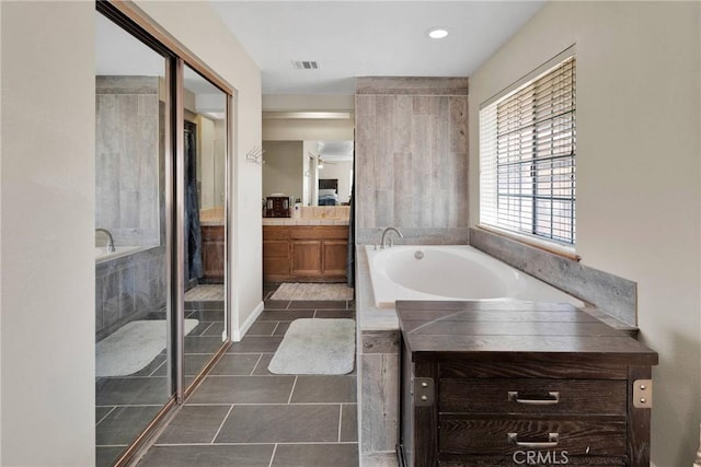 full bathroom featuring vanity, tile patterned floors, a bath, and visible vents