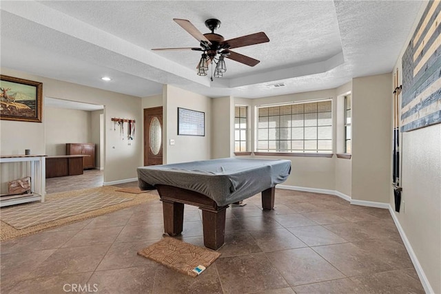 recreation room with baseboards, a raised ceiling, and a textured ceiling