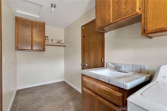 washroom featuring dark tile patterned floors, cabinet space, baseboards, and a sink