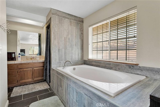 bathroom with tile patterned floors, a healthy amount of sunlight, a bath, and vanity