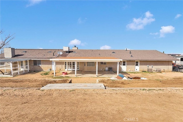 rear view of house featuring central AC, stucco siding, french doors, a chimney, and a patio