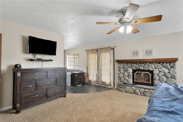 living area featuring a ceiling fan, carpet, baseboards, a fireplace, and a textured ceiling