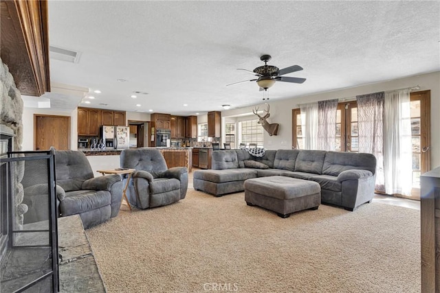 living room featuring visible vents, a textured ceiling, recessed lighting, carpet floors, and a fireplace