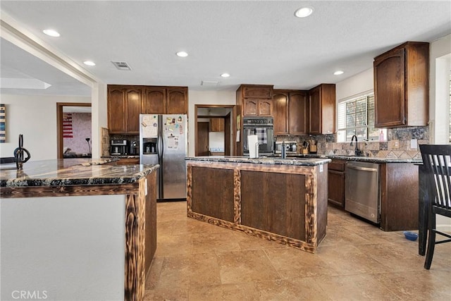 kitchen featuring tasteful backsplash, a kitchen island, visible vents, and stainless steel appliances