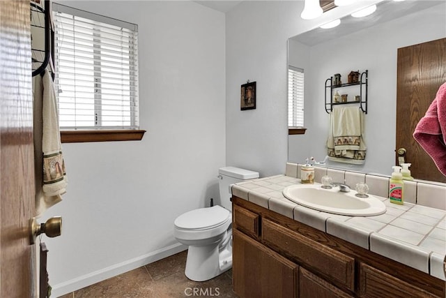 bathroom featuring vanity, toilet, baseboards, and tile patterned flooring