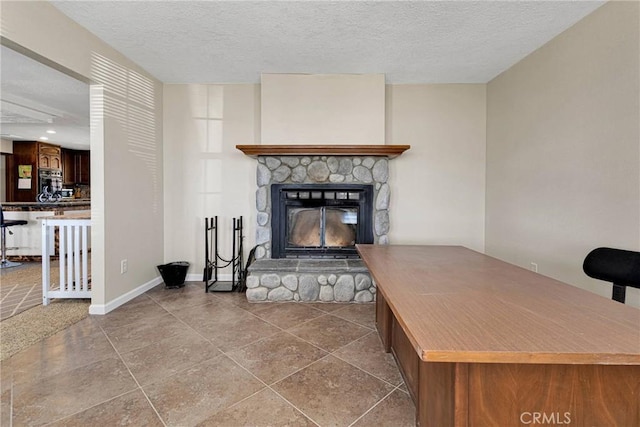 living area with a fireplace, a textured ceiling, and baseboards