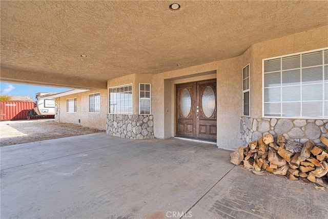 view of exterior entry with stone siding, stucco siding, and fence