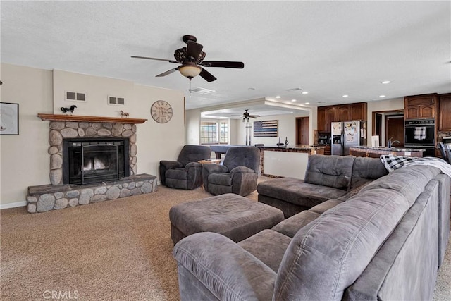 living room with visible vents, carpet flooring, and a stone fireplace