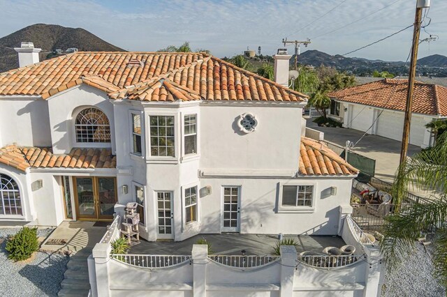 22633 Inspiration Pt, Canyon Lake, CA 92587 - view of front facade featuring stucco siding, a tile roof, fence, french doors, and a chimney