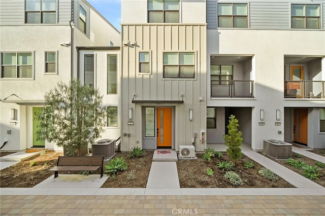 view of front of property featuring ac unit, central AC unit, board and batten siding, and stucco siding