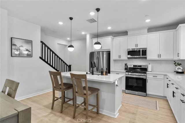 kitchen with visible vents, light wood-style flooring, light countertops, appliances with stainless steel finishes, and tasteful backsplash