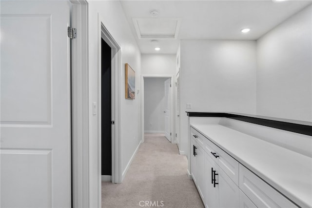 corridor featuring attic access, recessed lighting, baseboards, and light carpet