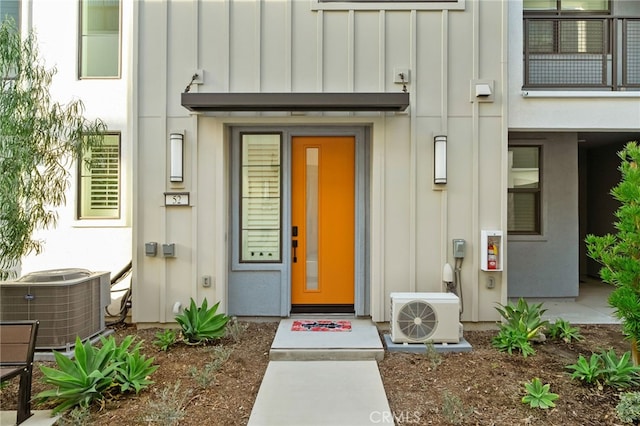 entrance to property with ac unit, cooling unit, and board and batten siding