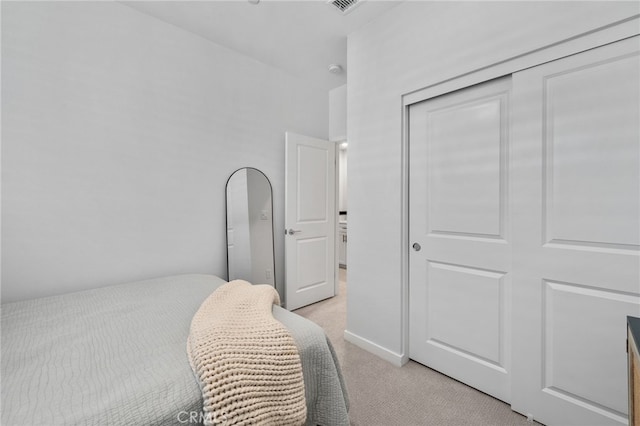 bedroom with a closet, visible vents, light colored carpet, and baseboards