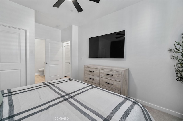 bedroom featuring connected bathroom, light colored carpet, baseboards, and a ceiling fan