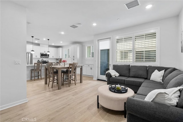 living area with recessed lighting, light wood-style floors, and visible vents