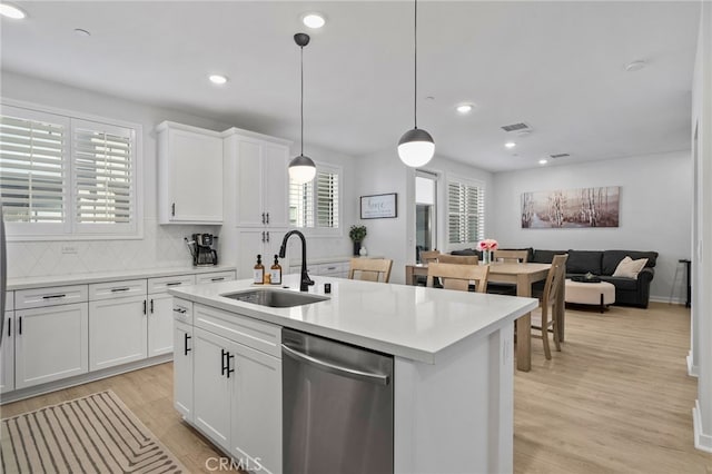 kitchen featuring light wood-type flooring, a sink, open floor plan, light countertops, and dishwasher